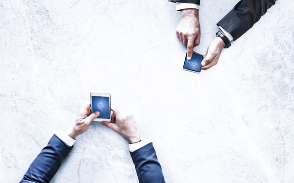two-people-holding-smartphones-over-table
