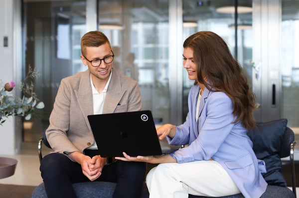 Två medarbetare arbetar tillsammans med hållbarhetsarbete på en laptop