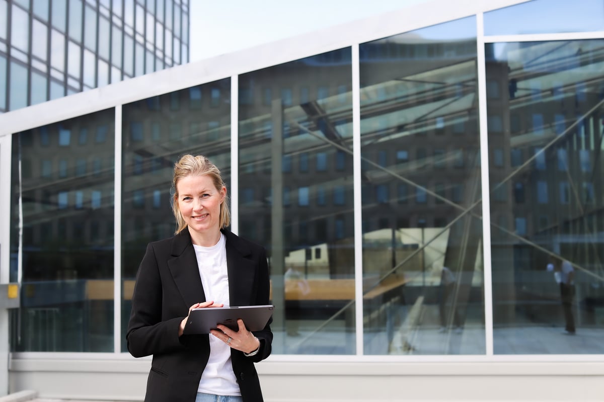 kvinne-stjerne-i-front-av-bygning-med-ipad