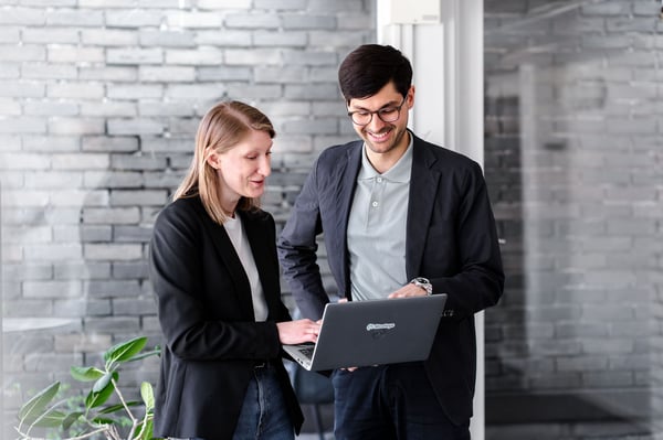 Två medarbetare diskuterar ISMS framför laptop