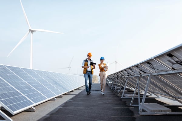 Två medarbetare bedömer ESG-risker med vindkraftsverk i bakgrunden