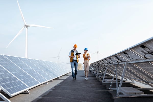 Two co-workers managing ESG risks with wind turbines in the background